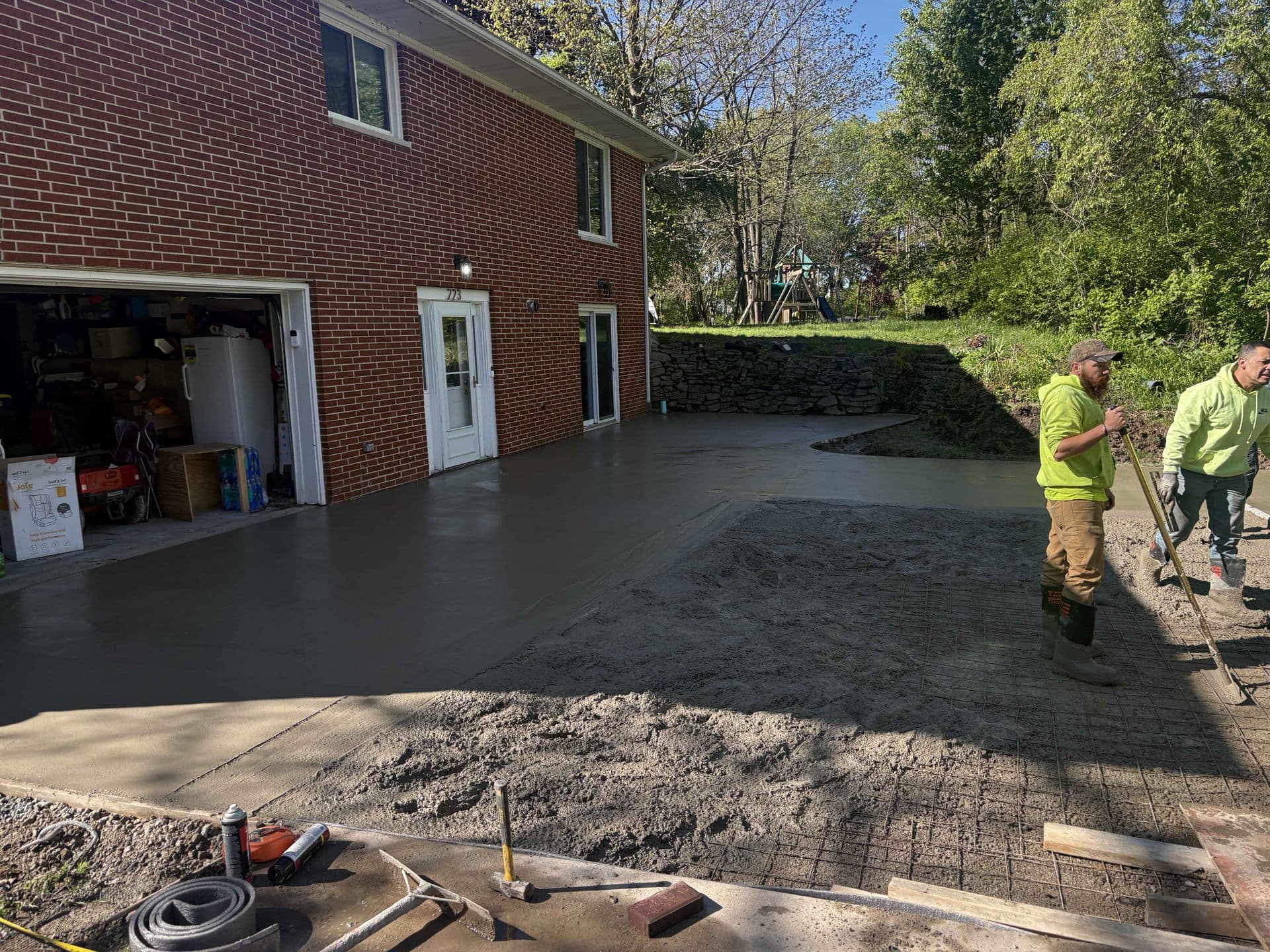 A crew finishing a freshly poured concrete driveway