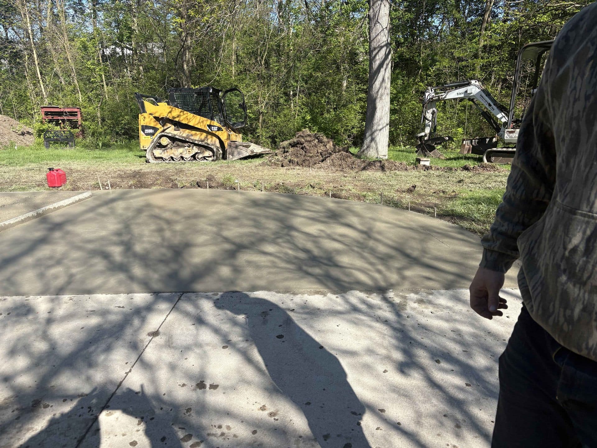 A fresh concrete slab with a skid steer and mini excavator on site