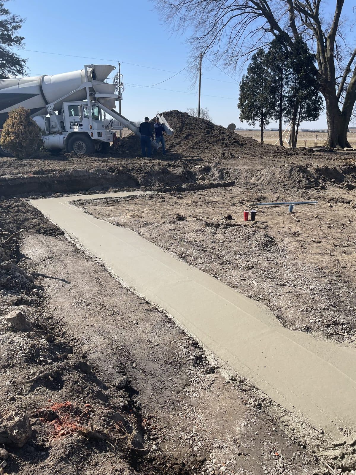 A new concrete walkway across a yard with a mini excavator working behind it