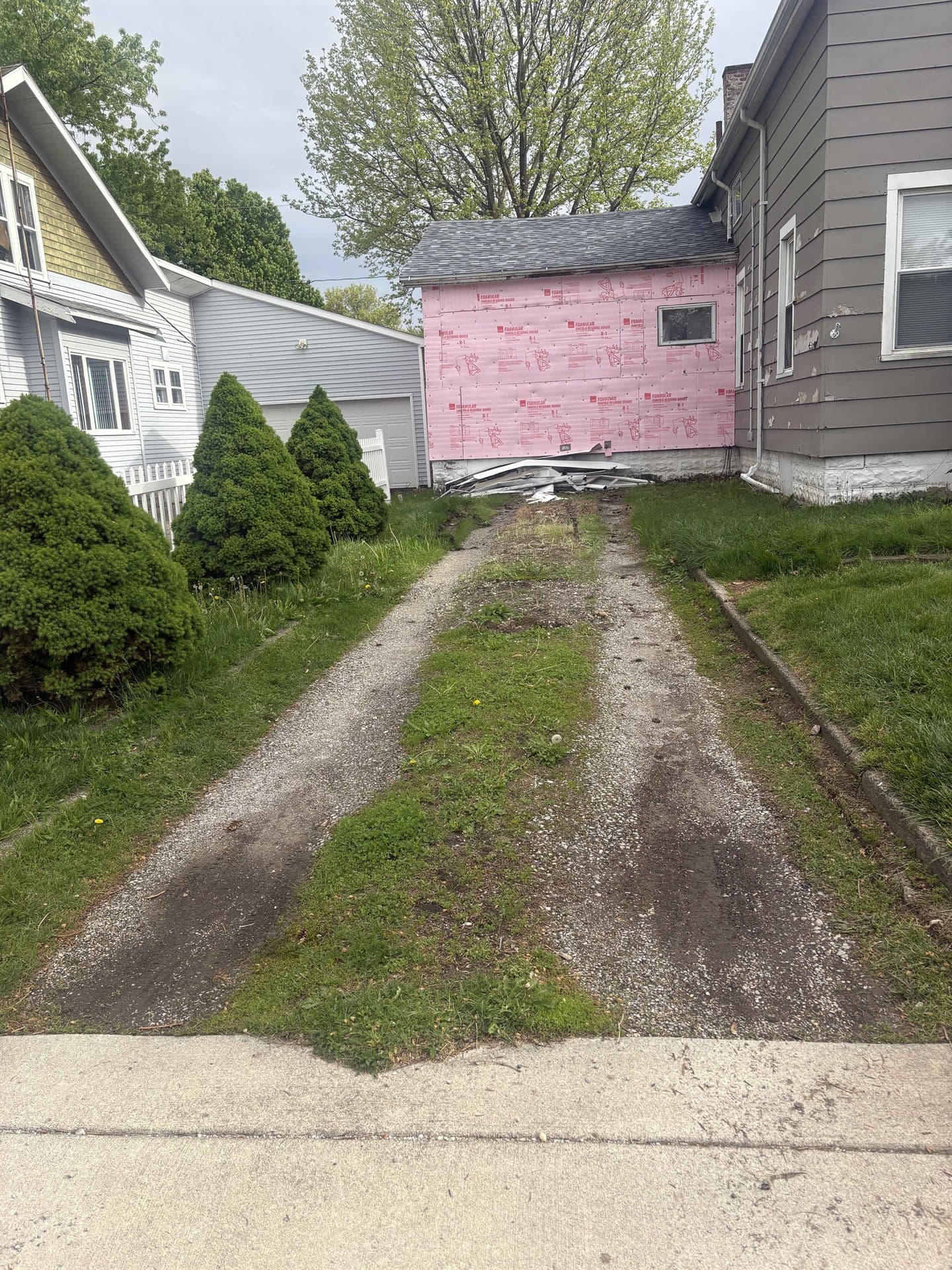 A worn dirt and gravel driveway grown over with grass