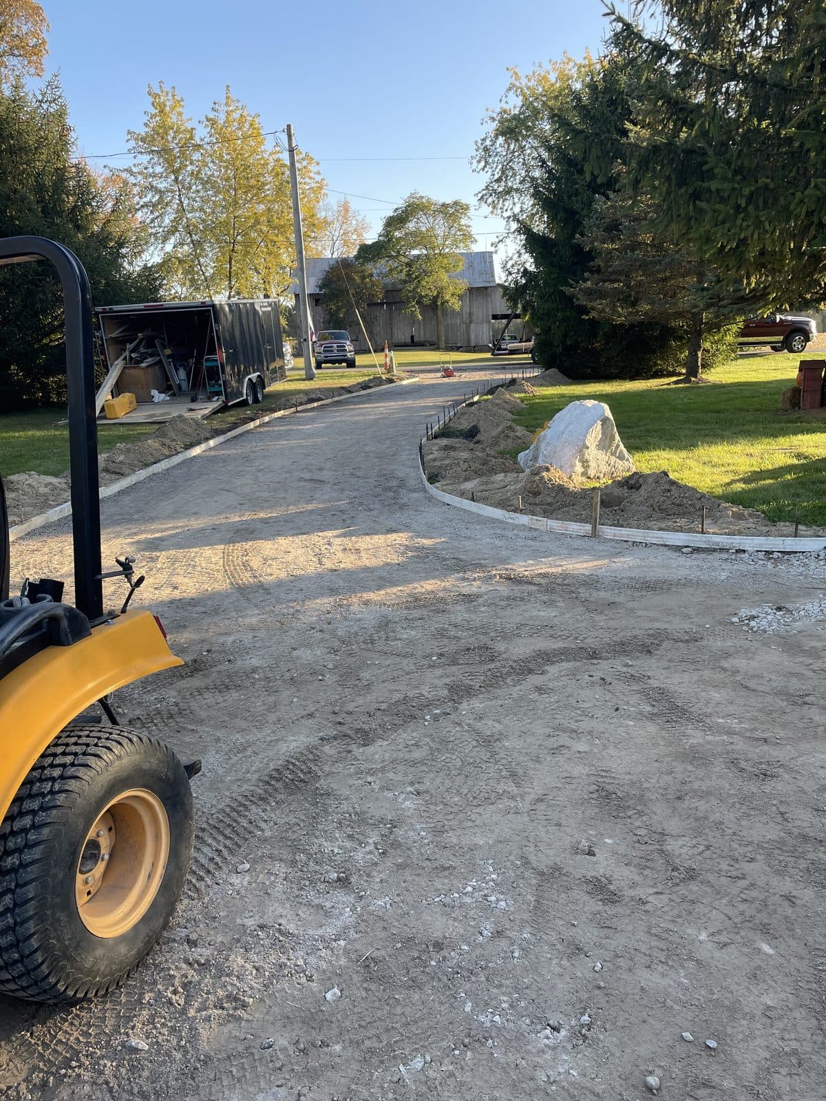 A wheel loader grading and spreading stone on a gravel driveway