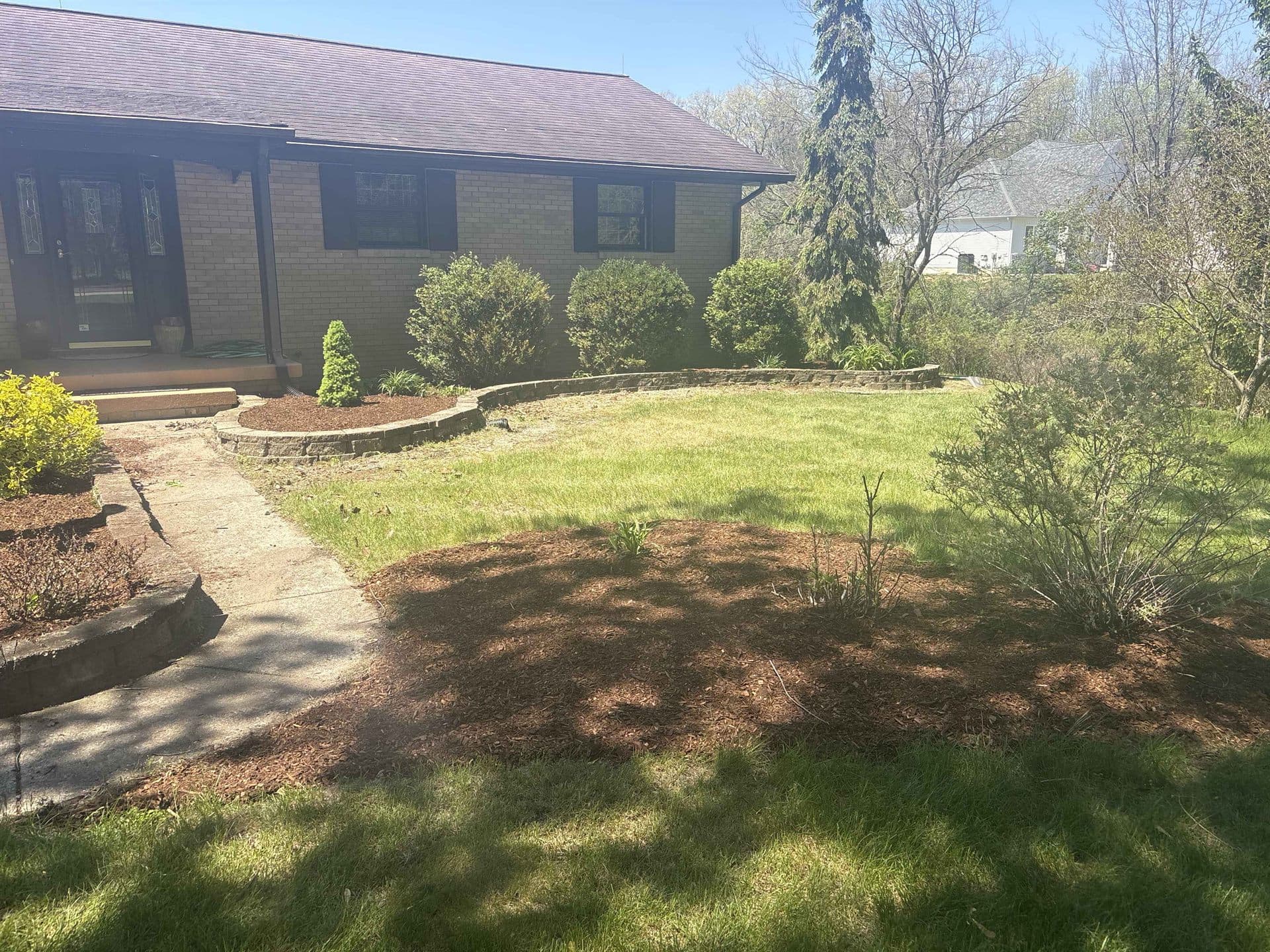A tidy front yard with fresh mulch beds and a stone retaining wall