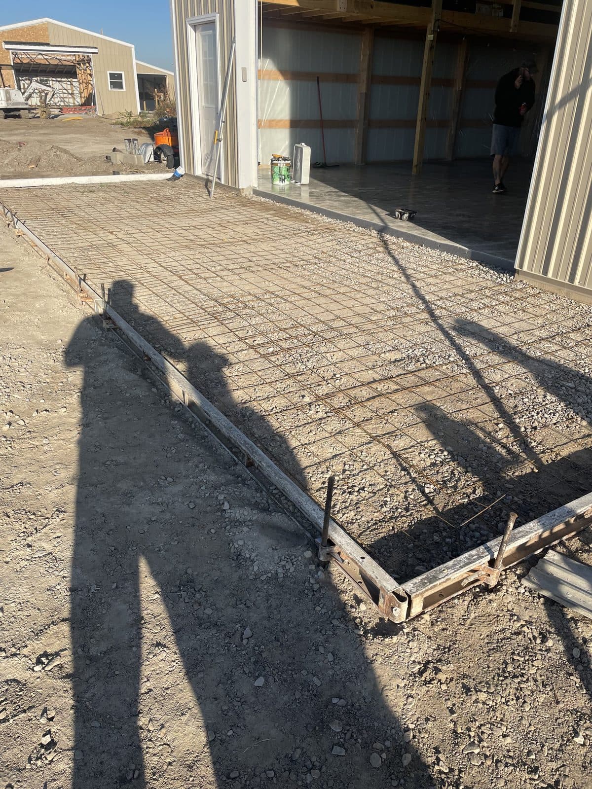 A freshly poured concrete pad in front of a garage