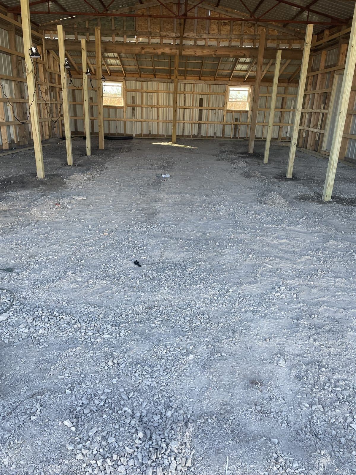 A freshly poured concrete floor inside a wood-framed pole barn