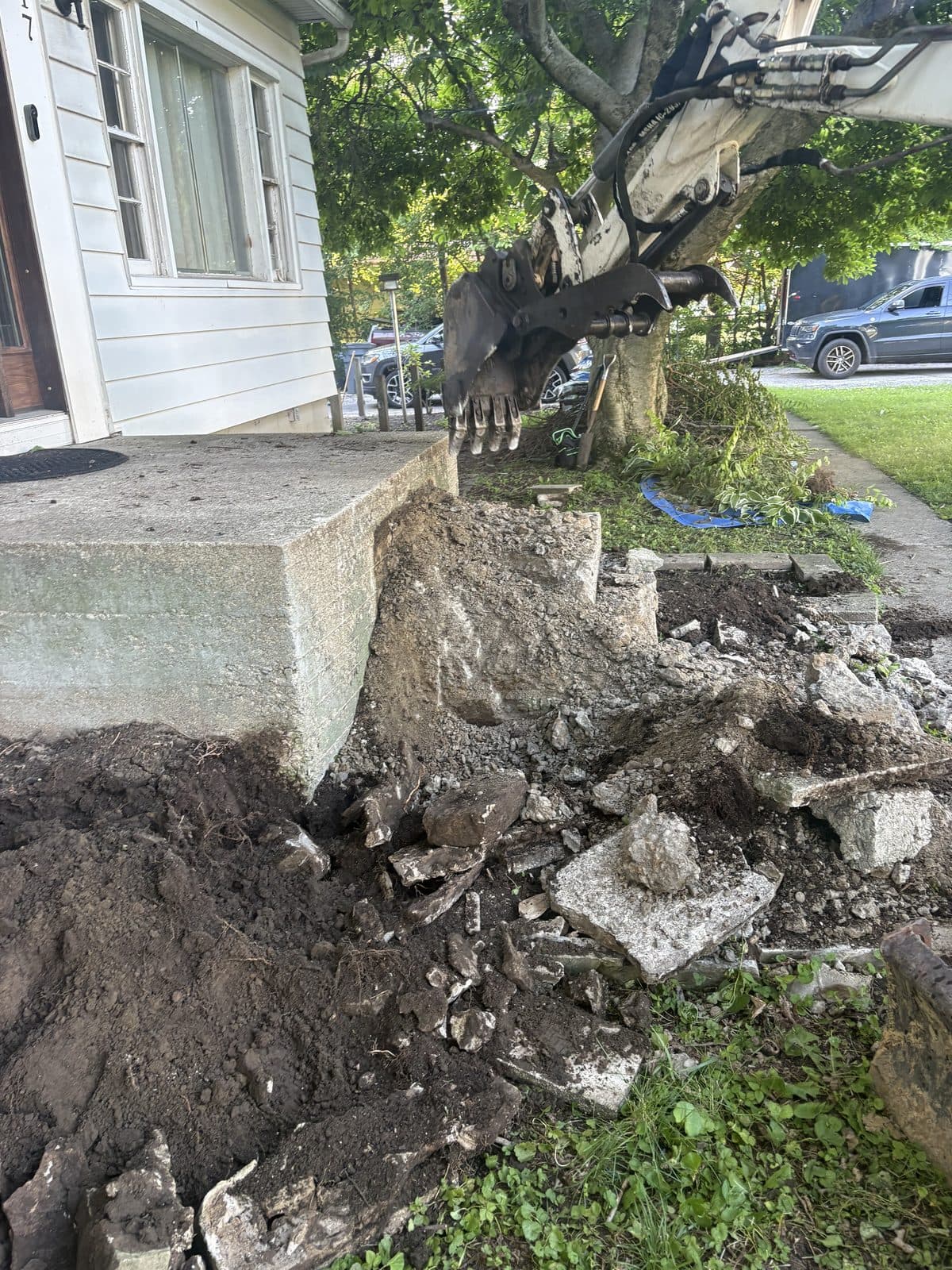 Demolition debris and broken concrete being cleared from a residential site