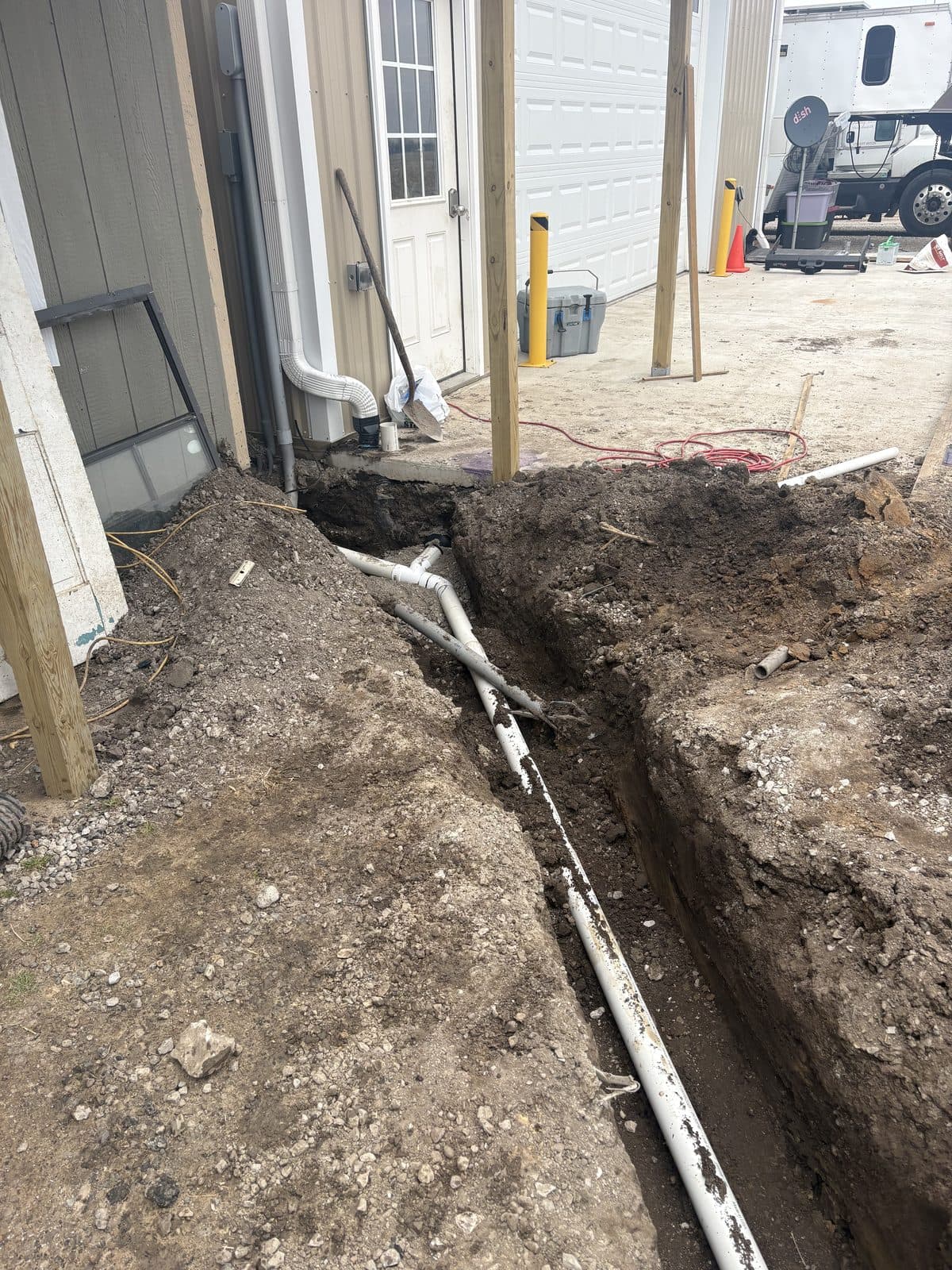 A drainage trench with pipe dug along the foundation of a house