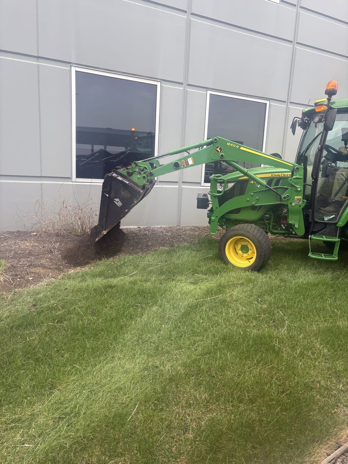 A compact tractor doing grounds work on a manicured commercial lawn